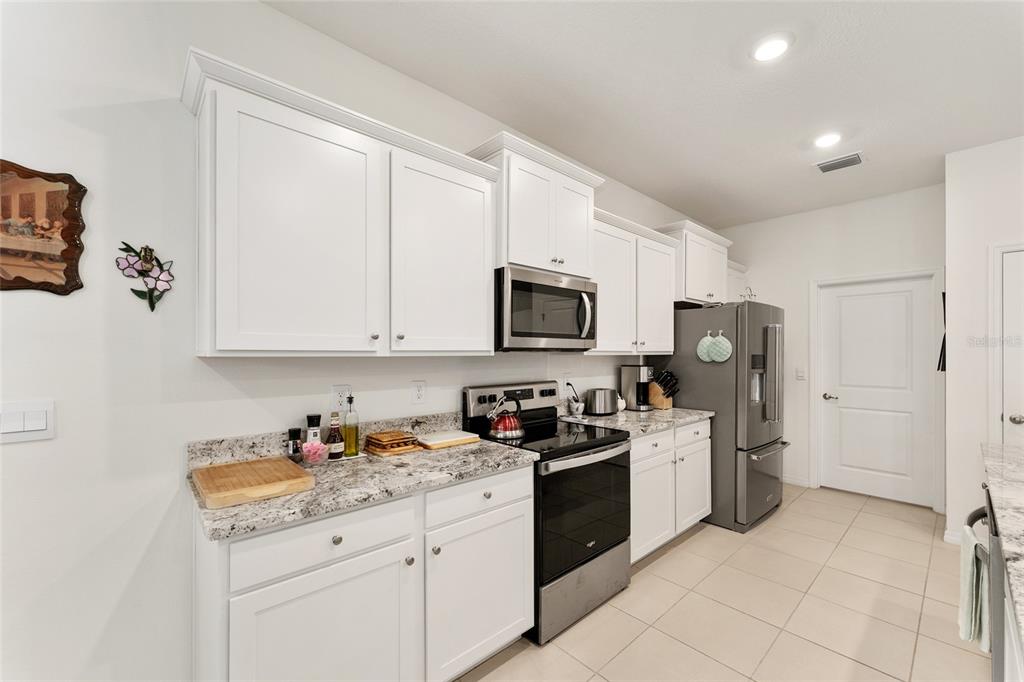 6175 Southwest 88th Loop Ocala, FL 34476 - Photo 15 of 56 a kitchen with stainless steel appliances granite countertop a refrigerator sink and white cabinets