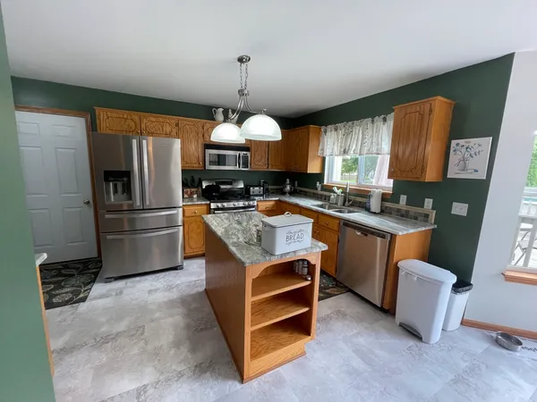 a kitchen with stainless steel appliances granite countertop a sink a stove and a refrigerator