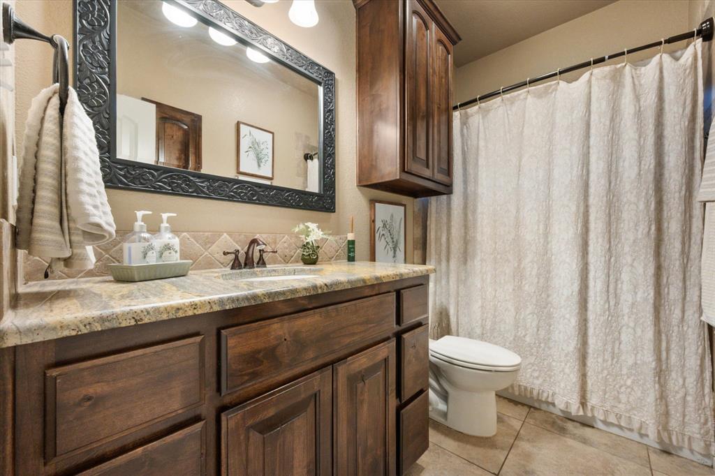 3715 Lonesome Creek Road Granbury, TX 76049 - Photo 33 of 40 a bathroom with a granite countertop sink toilet and mirror