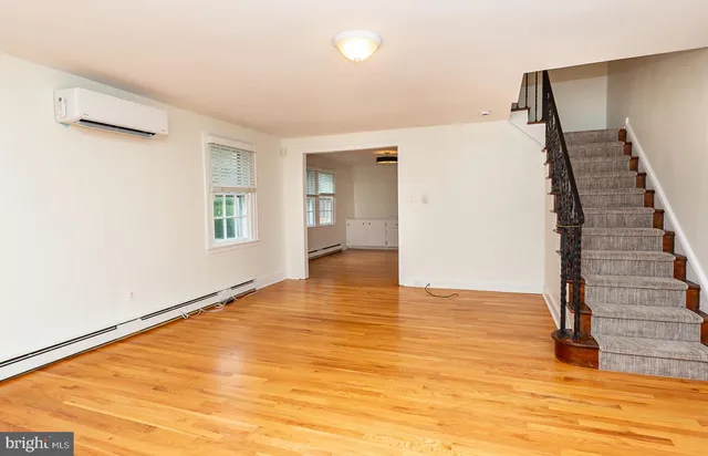 a view of an empty room with wooden floor and stairs