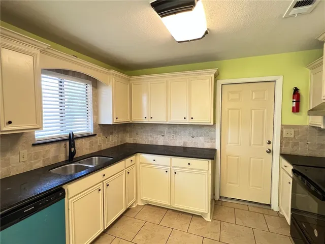 a kitchen with a sink dishwasher a refrigerator and cabinets