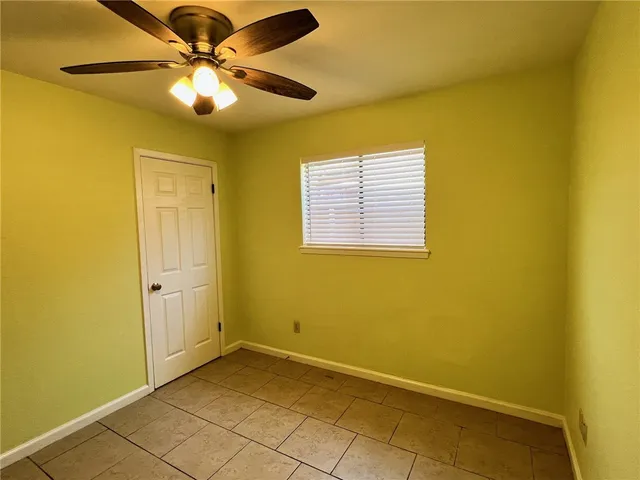 an empty room with a ceiling fan and a window