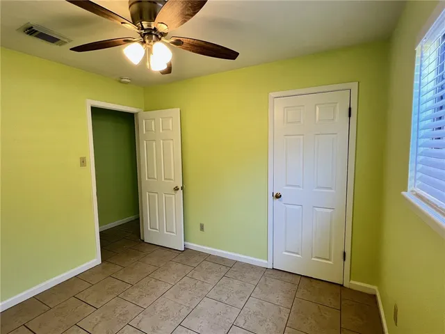 a view of an empty room with window and a ceiling fan