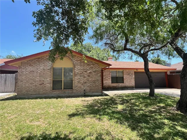 a front view of house with yard and trees in the background