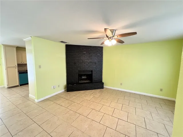 an empty room with a ceiling fan and a fireplace