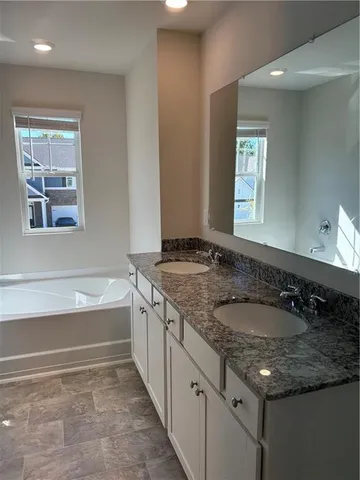 a bathroom with a granite countertop sink and a bathtub
