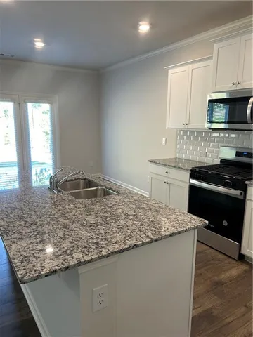 a kitchen with stainless steel appliances granite countertop a sink stove and cabinets