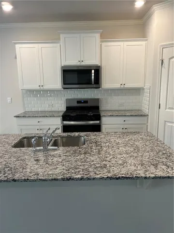 a kitchen with kitchen island granite countertop a sink and a stove top oven
