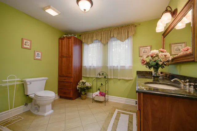 a bathroom with a sink mirror toilet and next to a window