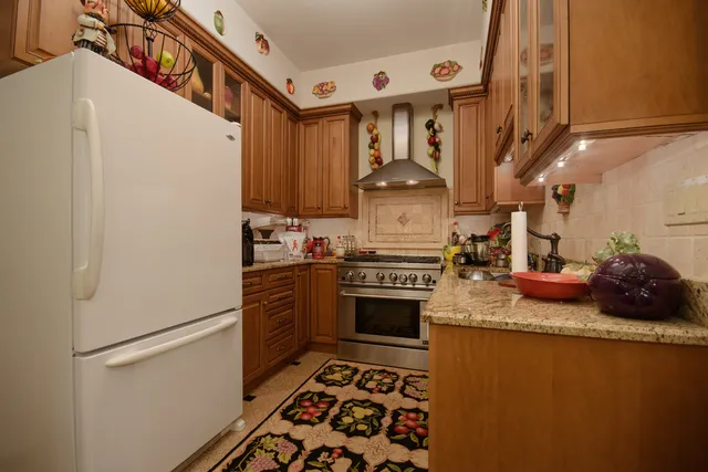 a kitchen with stainless steel appliances granite countertop a refrigerator a stove and a sink with wooden floor