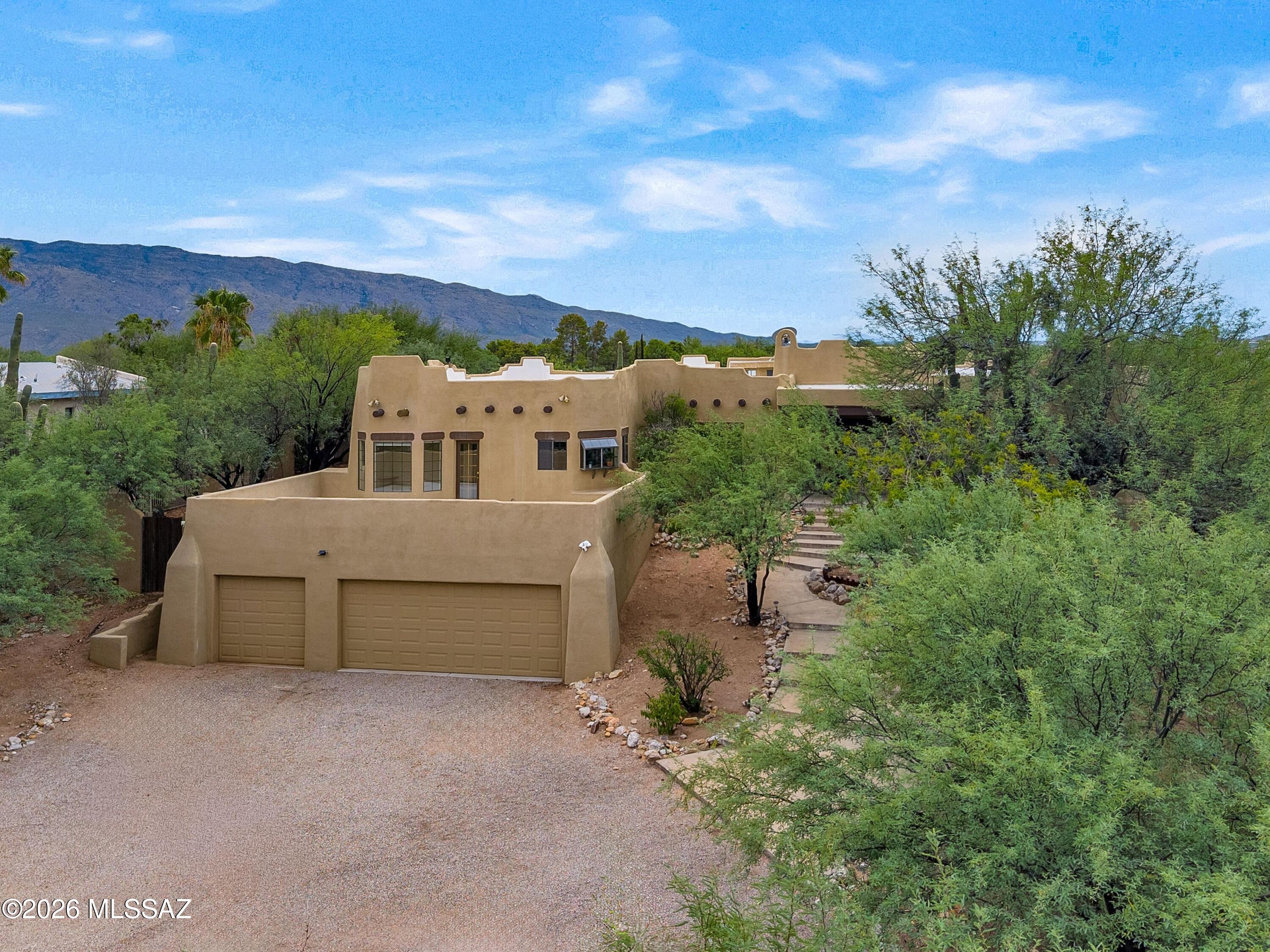 12160 East Tanque Verde Road Tucson, AZ 85749 - Photo 49 of 53 Front elevation showing the home's stepped parapet rooflines and desert xeriscaping against a mountain backdrop.