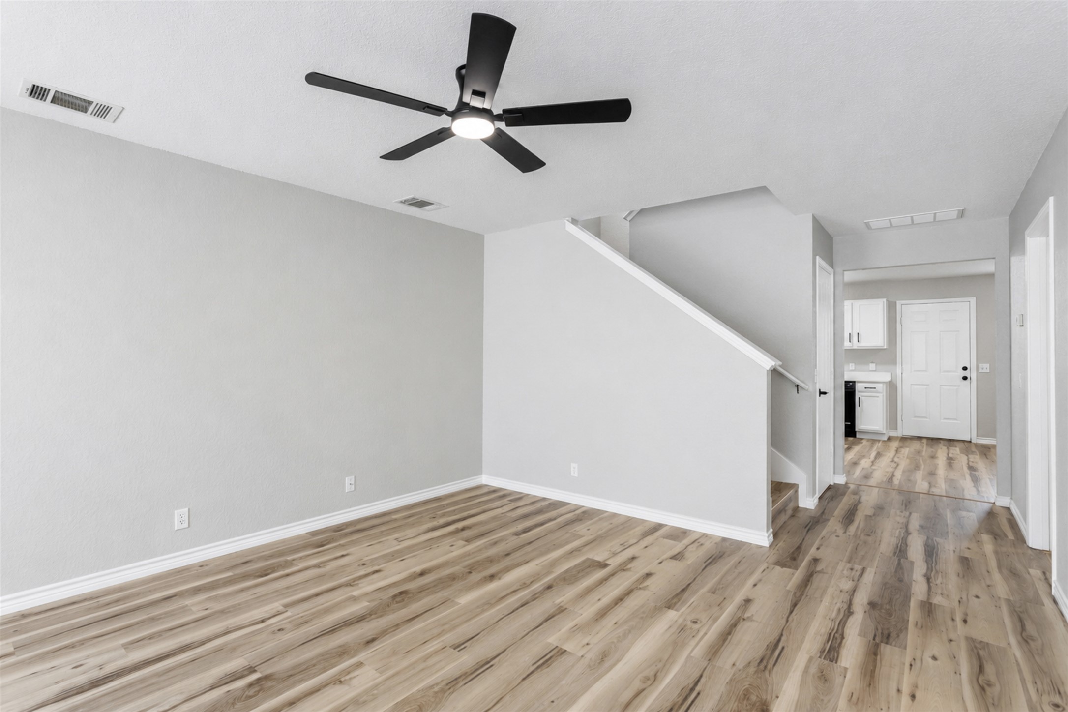 4523 Secure Lane Austin, TX 78725 - Photo 5 of 40 A versatile living area with a ceiling fan, complemented by sleek flooring and a clear path to the home's entry.