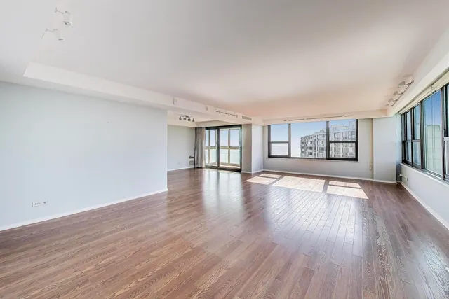 a view of an empty room with window and wooden floor