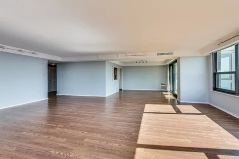 a view of a livingroom with wooden floor and kitchen