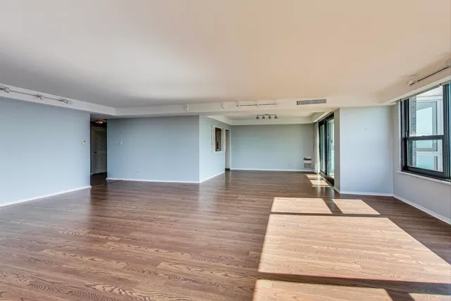 a view of a livingroom with wooden floor and kitchen