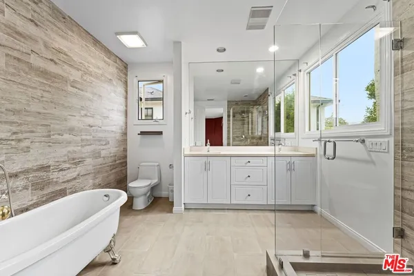 a bathroom with a granite countertop sink mirror bathtub and toilet
