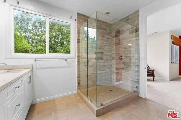 a bathroom with a shower and a sink a window