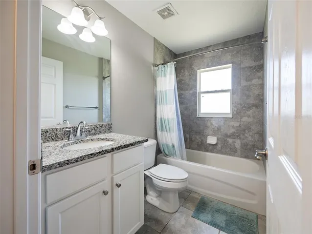 a bathroom with a granite countertop sink toilet mirror vanity and bathtub