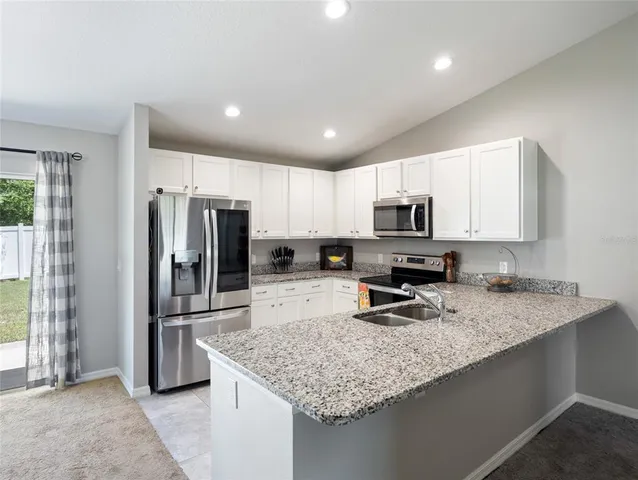 a kitchen with granite countertop a refrigerator and a sink