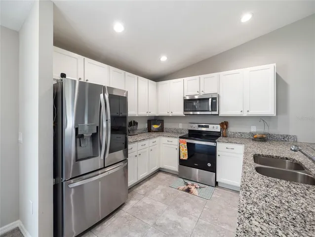 a kitchen with granite countertop a refrigerator sink and stove