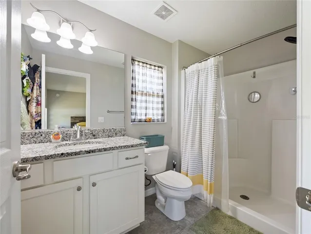 a bathroom with a granite countertop sink toilet a mirror a vanity and shower