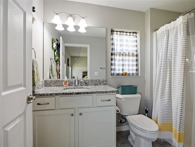 a bathroom with a granite countertop toilet a sink and a mirror