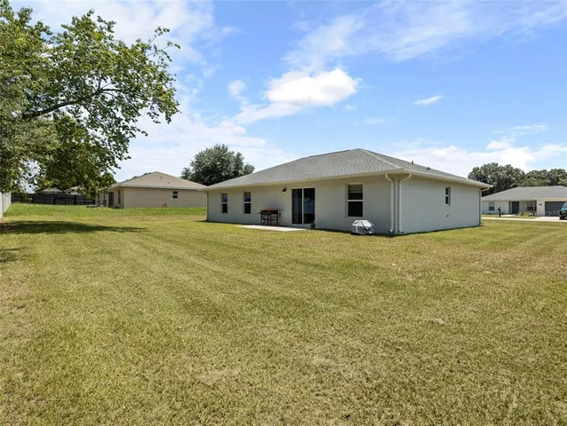 a view of house with outdoor space and trees in the background