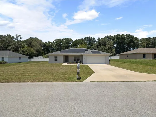a front view of house with yard and trees in the background