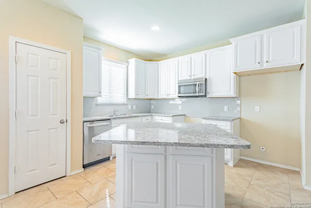 a kitchen with granite countertop white cabinets and a sink