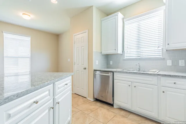 a kitchen with white cabinets and sink