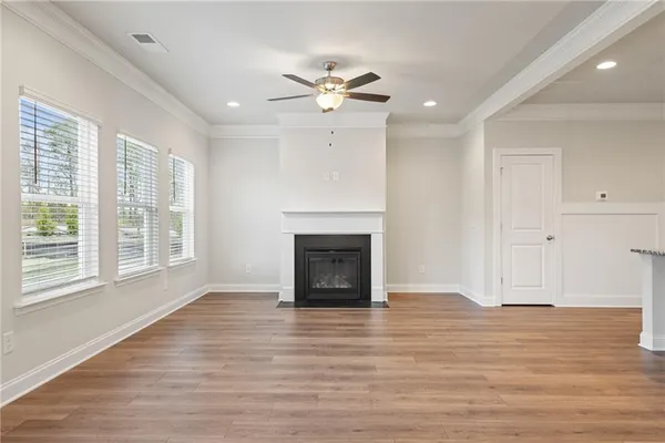 a view of an empty room with wooden floor fireplace and a window