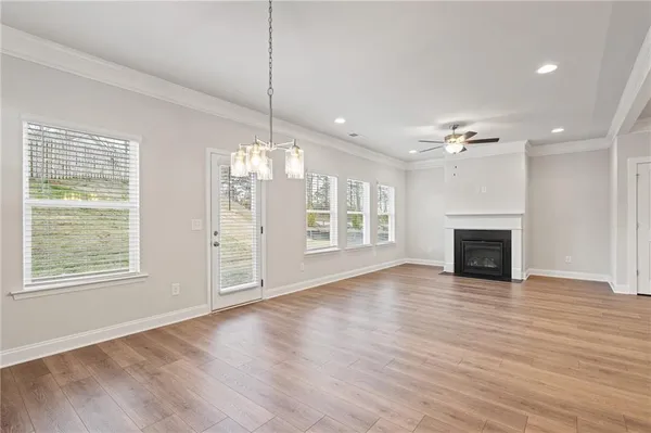 a view of an empty room with wooden floor fireplace and a window