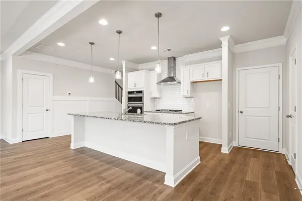 a kitchen with kitchen island a sink a stove a refrigerator and white cabinets