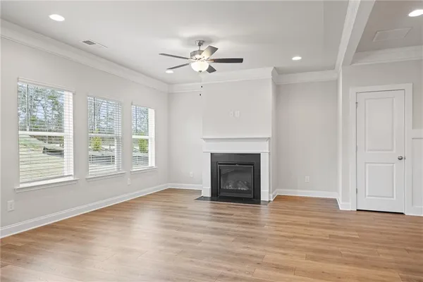 an empty room with wooden floor fan and windows