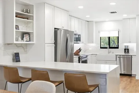 a kitchen with stainless steel appliances a dining table chairs refrigerator and sink