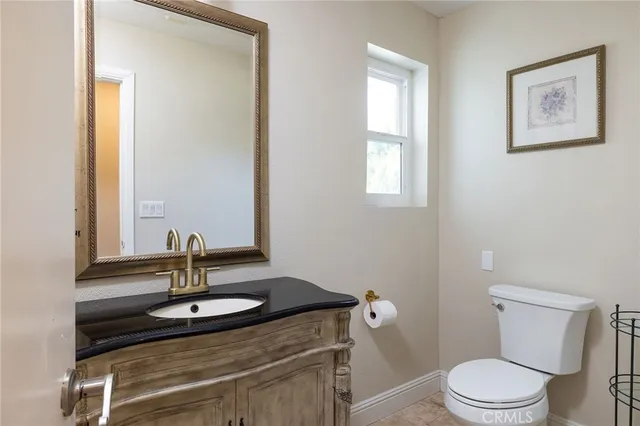a bathroom with a granite countertop sink toilet and mirror
