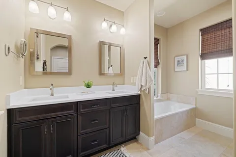 a bathroom with a tub double sink window and mirror