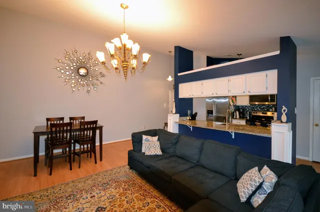 a living room with furniture a chandelier and kitchen view