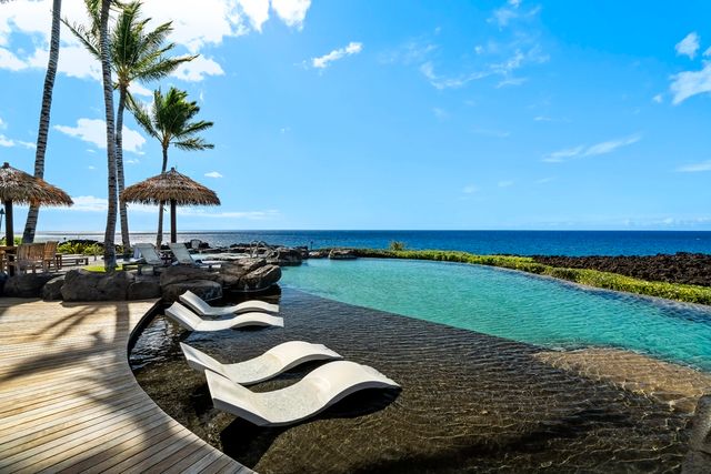 a view of a swimming pool with lawn chairs under an umbrella