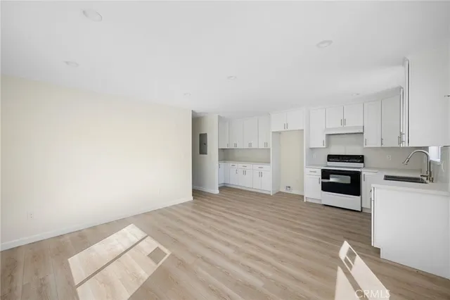 a kitchen with granite countertop a refrigerator oven a stove top oven and white cabinets