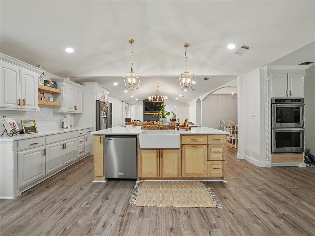 6701 Nauert Road Forest Hill, TX 76140 - Photo 10 of 40 Spacious kitchen featuring an expansive center island, farm sink, light wood-finish flooring, white cabinetry with gold-tone hardware, and double wall ovens