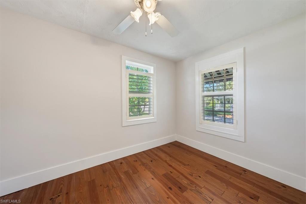 1984 Frederick Street Naples, FL 34112 - Photo 14 of 25 an empty room with wooden floor chandelier fan and windows