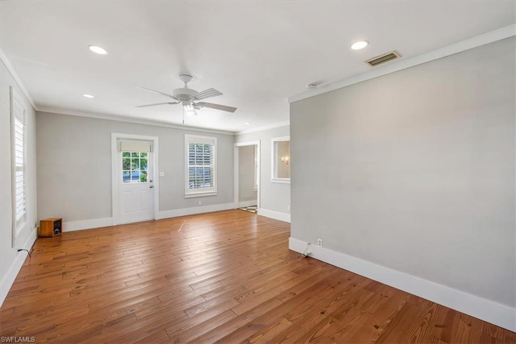 1984 Frederick Street Naples, FL 34112 - Photo 4 of 25 an empty room with wooden floor chandelier fan and windows