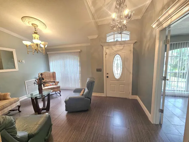 a living room with furniture a chandelier and wooden floor