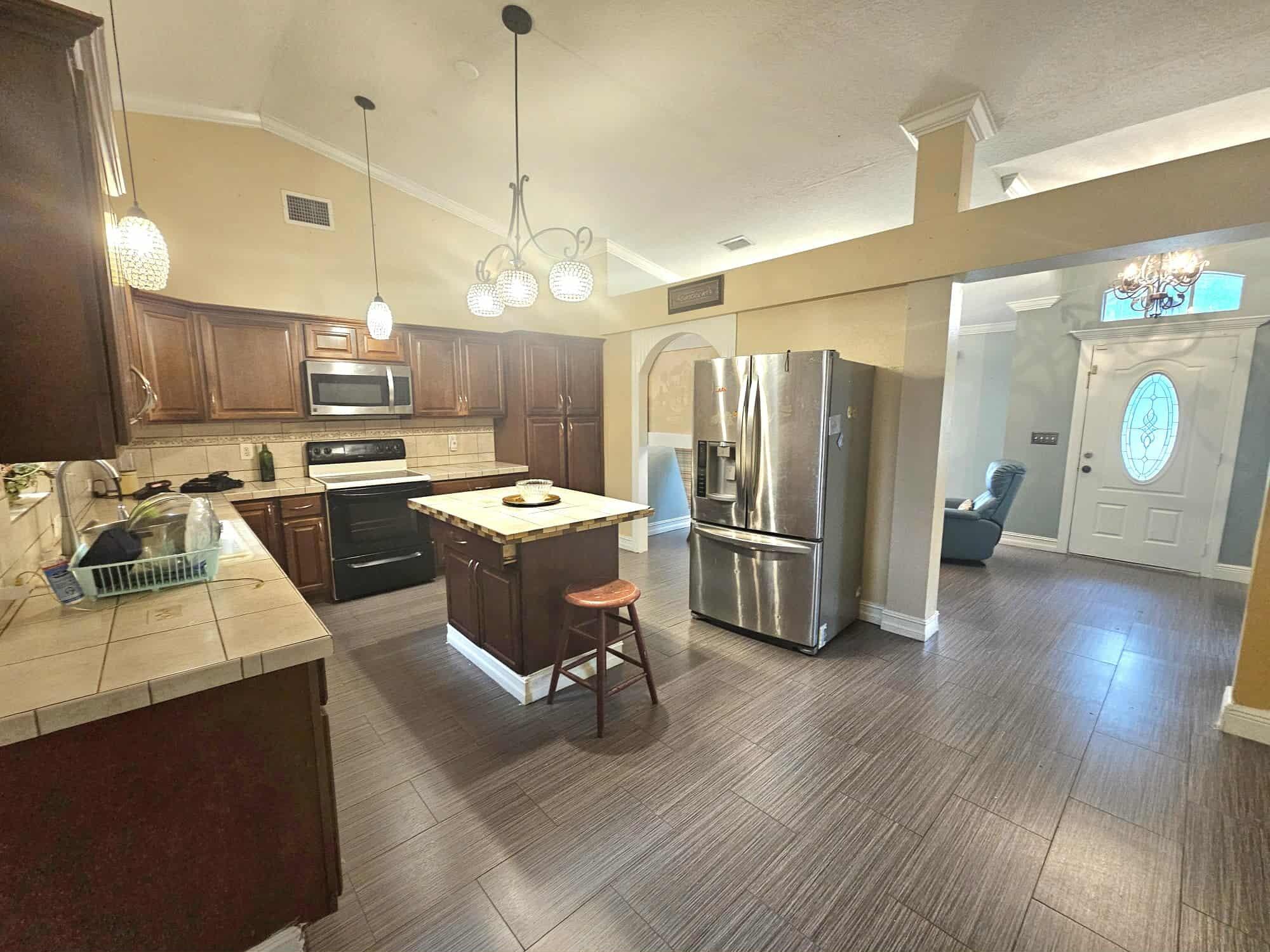 3641 Southwest Parsons Street Port St. Lucie, FL 34953 - Photo 6 of 11 a kitchen with stainless steel appliances granite countertop a refrigerator a sink dishwasher a stove and a dining table with wooden floor