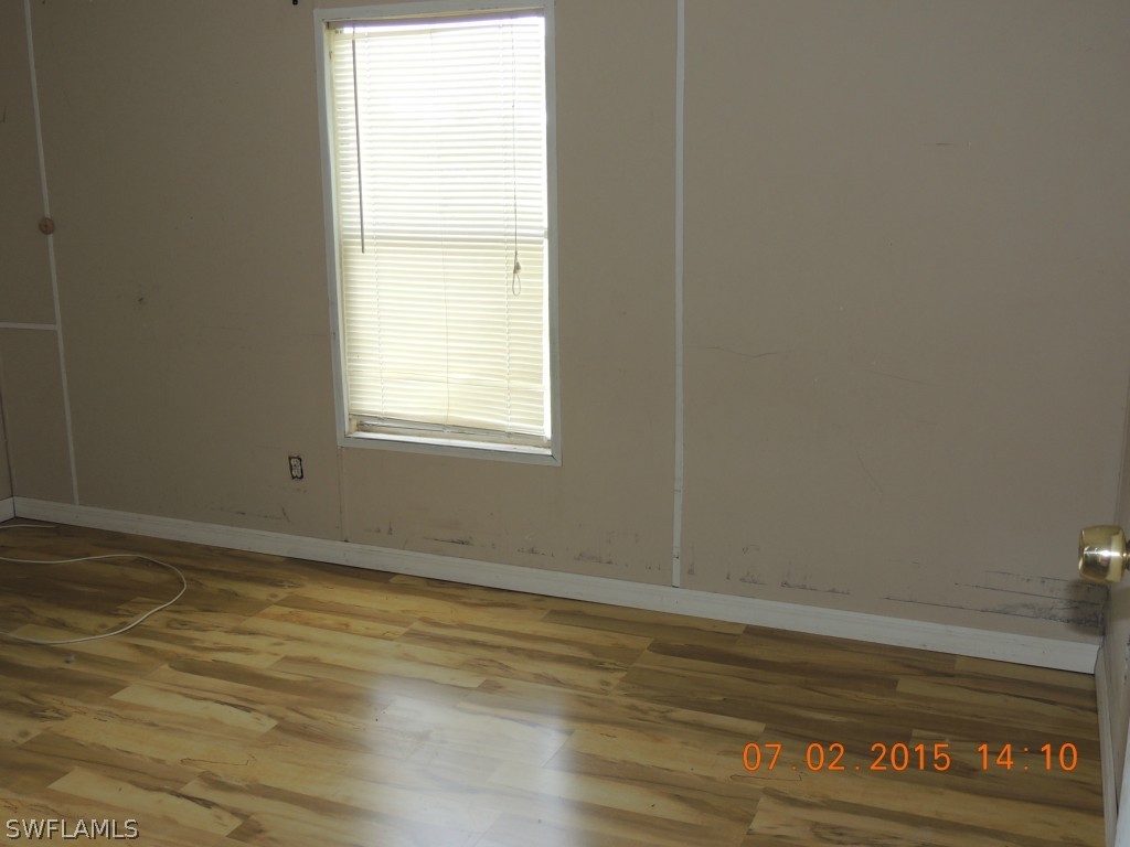 195 G Road LaBelle, FL 33935 - Photo 3 of 9 a view of an empty room with wooden floor and a window