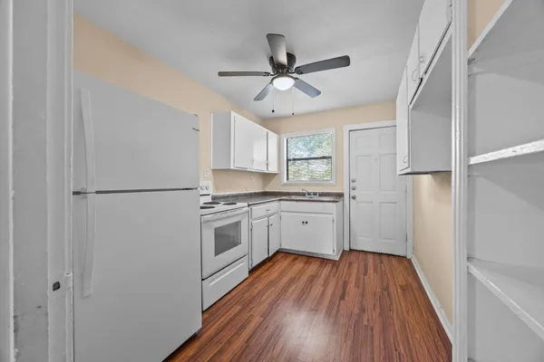 a kitchen with a refrigerator a stove cabinets and wooden floor