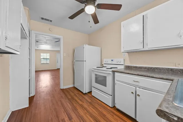 a kitchen with granite countertop white cabinets and white appliances
