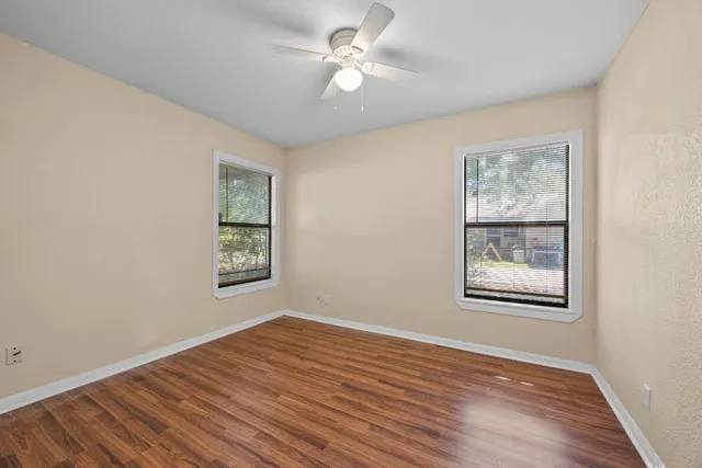 a view of an empty room with window and wooden floor