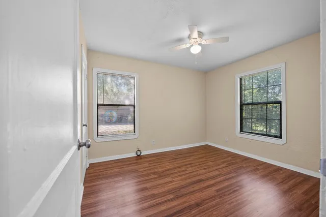 a view of an empty room with a window and wooden floor